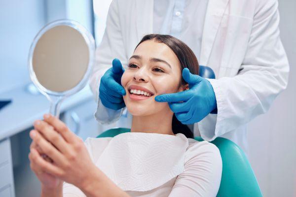 woman smiling in mirror at dentist office in arvada co