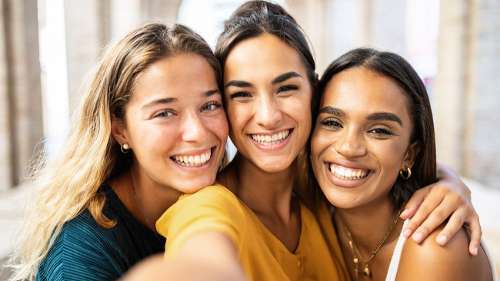 Three friends smiling together, showing bright healthy teeth after cosmetic dental treatment