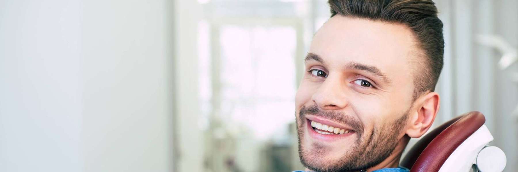Smiling man seated in a dental chair with clean white teeth after a cosmetic dentistry visit